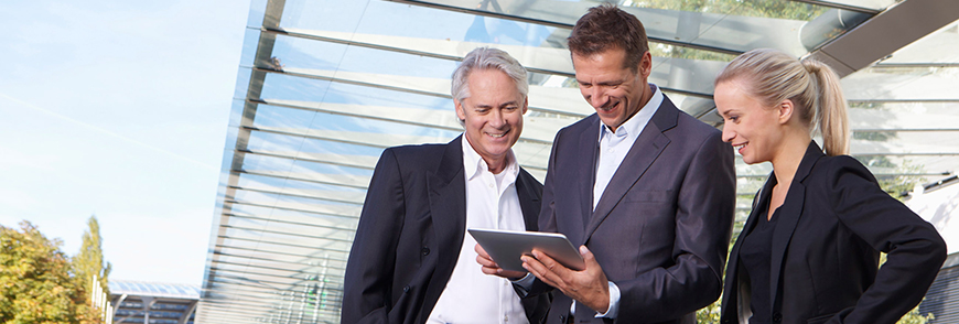 Munich, Germany --- Germany, Bavaria, Munich, Business people using digital tablet, smiling --- Image by © Carlos Hernandez/Westend61/Corbis